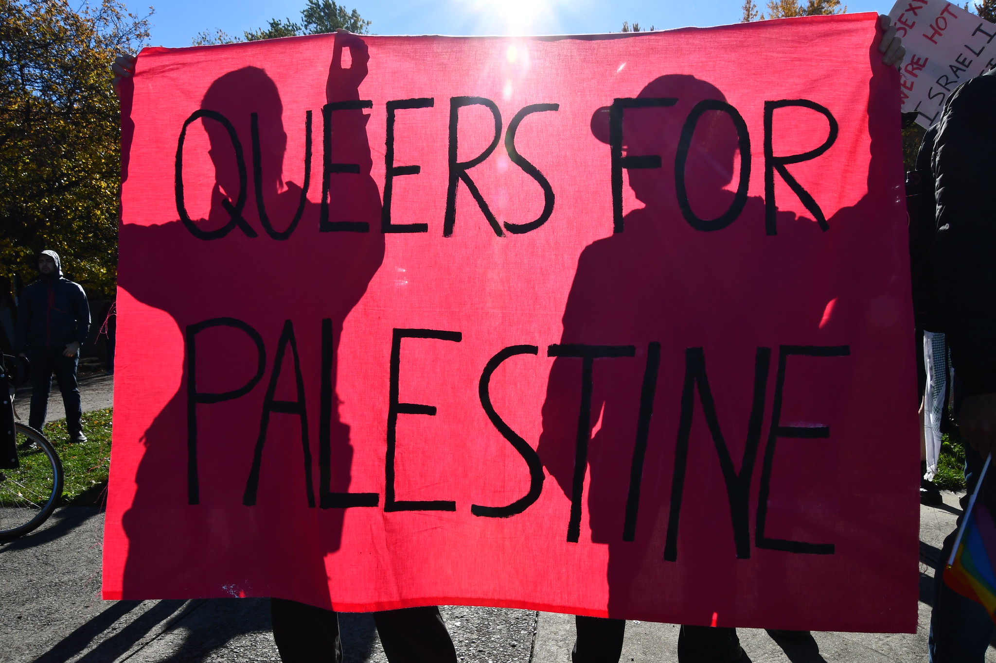 Deux personnes tenant une bannière rose sur laquelle il est écrit "queers for palestine"